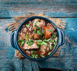 Meat stew with vegetables and herbs on old wooden table